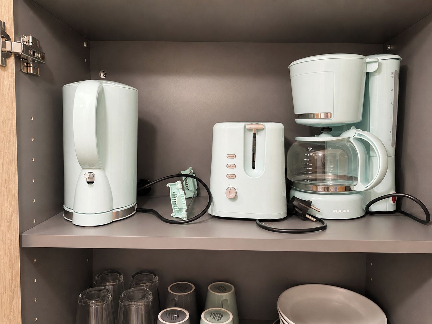 Eine Küche mit Kaffeemaschine, Toaster und einer Waage. Darunter befindet sich ein Regal mit mehreren Glasbehältern.