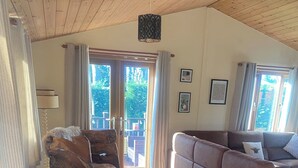 Ett rymligt vardagsrum med ett matbord i trä, en soffa och en balkong med gardiner.