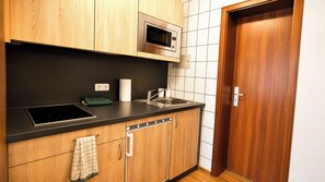 A kitchen with a built-in microwave, a sink, and wooden cabinets.