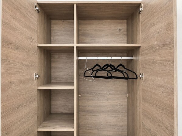A wooden wardrobe with multiple shelves and a hanging rod.