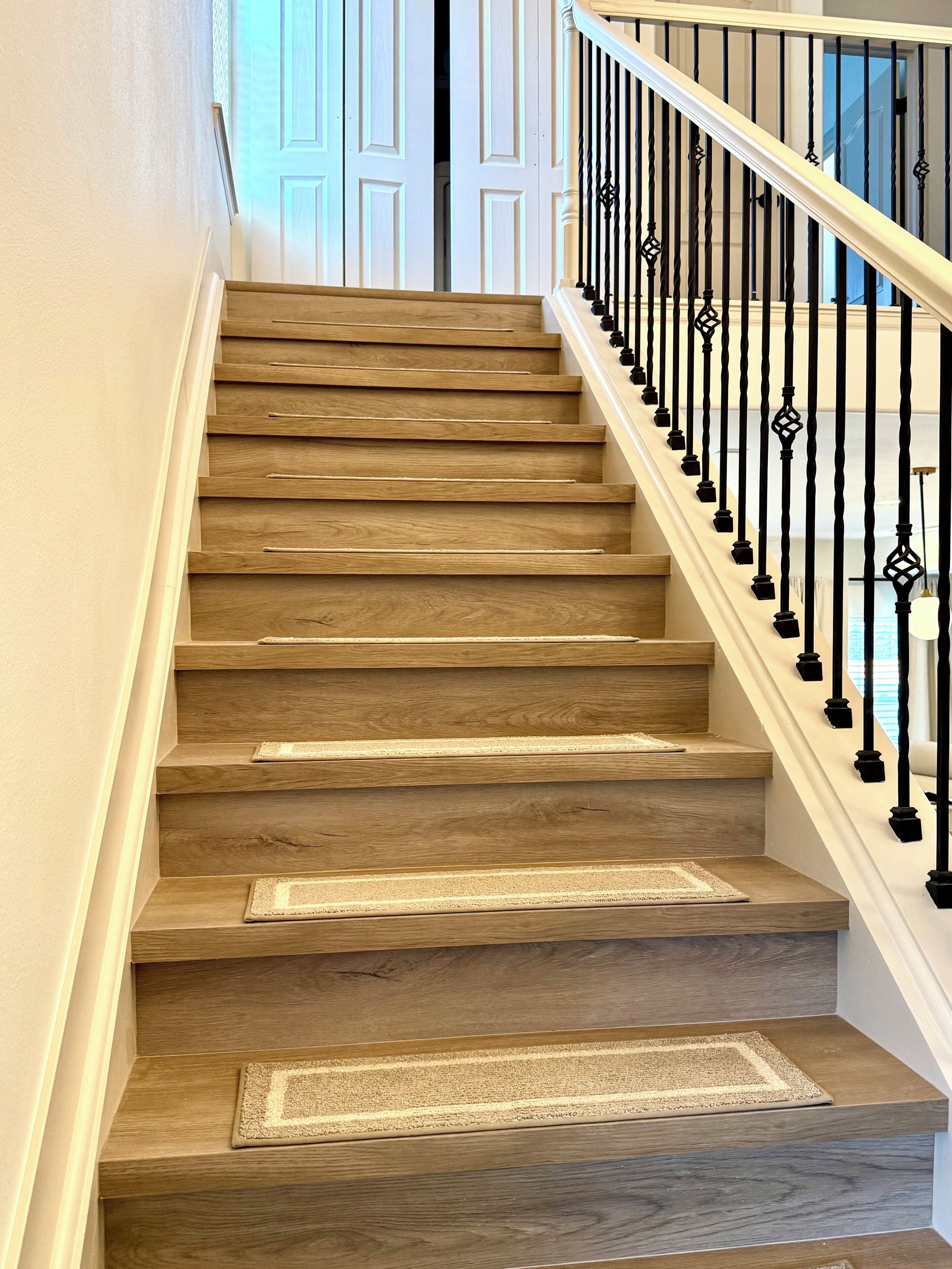 A wooden staircase with a white handrail and black balusters.