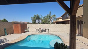 A swimming pool with a wooden deck and a covered patio area. - Spacious 4-bedroom house in lovely Bakersfield with AC (Bakersfield)