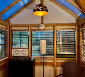 A room with a sloped ceiling, a clock, and a standing lamp.