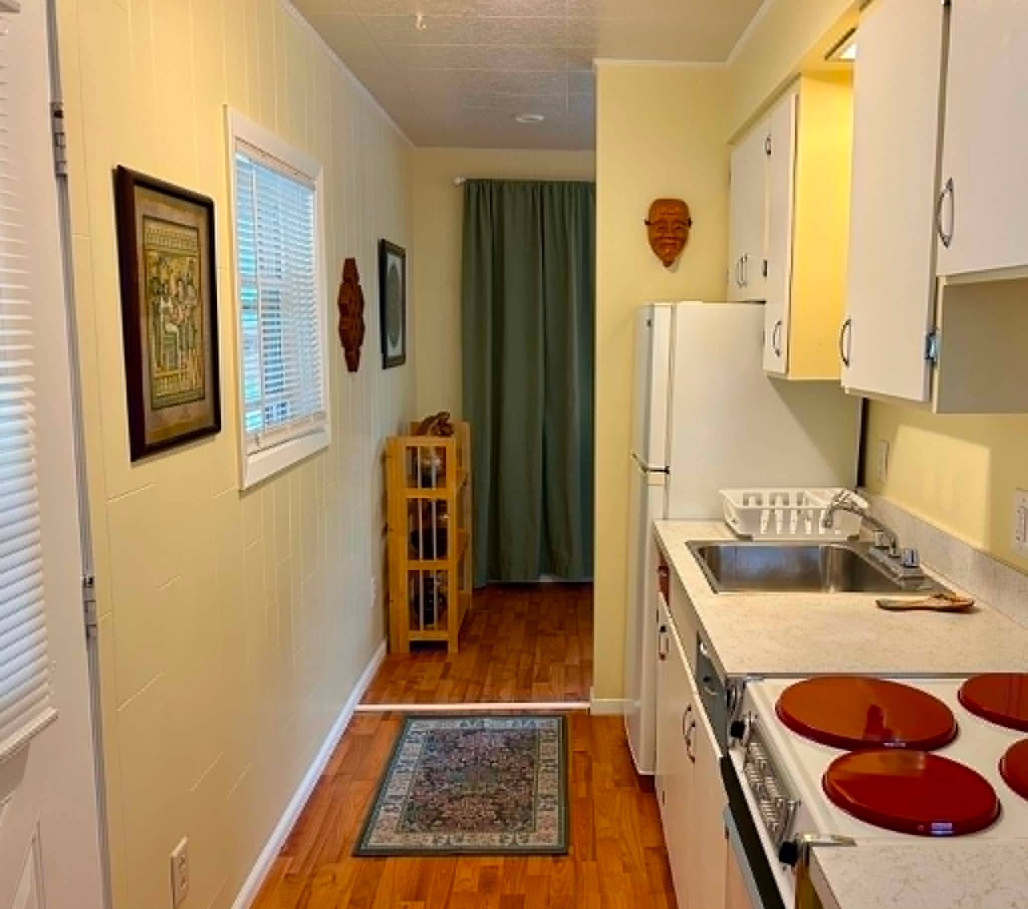 A compact kitchen with a sink, stove, and cabinets.