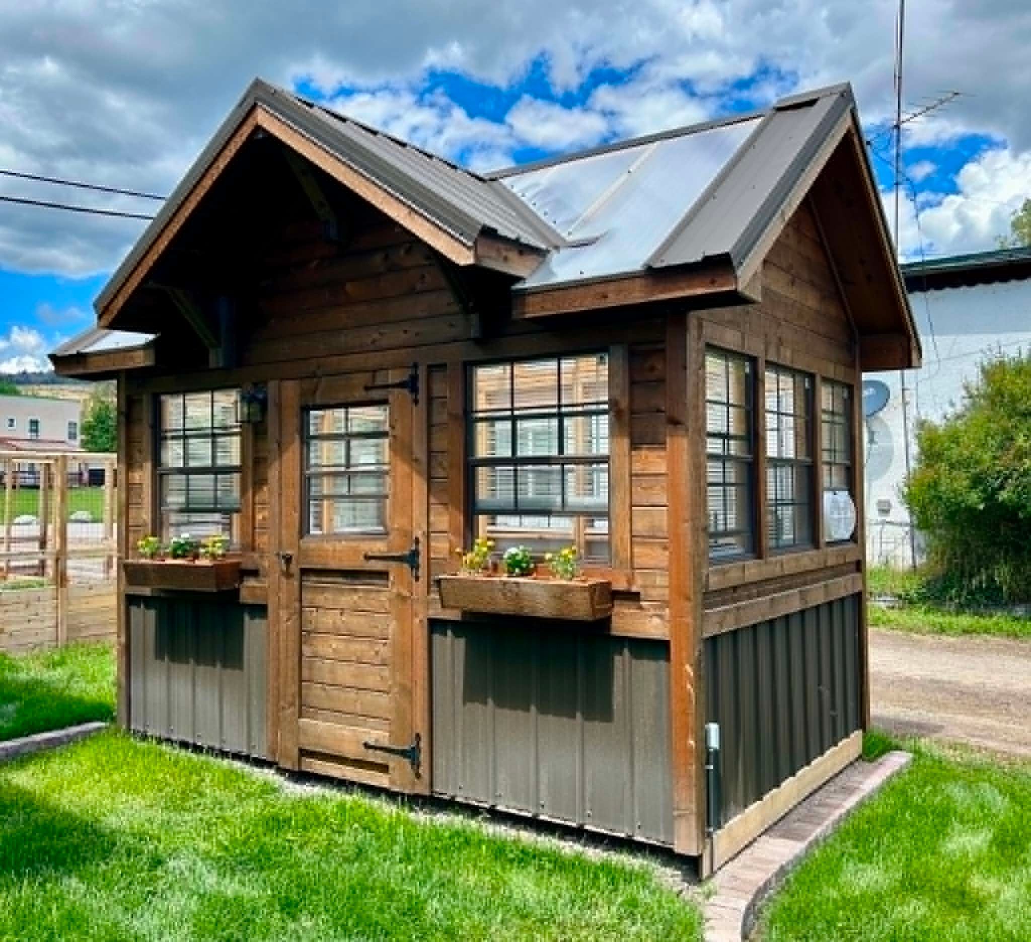 A wooden cabin with a pitched roof, large windows, and a door with a window above it.
