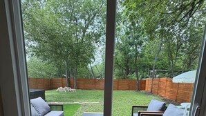 A sliding glass door leading to an outdoor patio with a patterned rug, two sofas, and a coffee table.