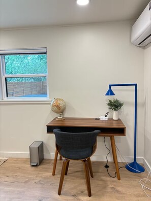 A study area with a desk, chair, globe, lamp, and air conditioning unit.