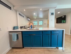 A modern kitchen with a central island, built-in blue cabinets, and a stainless steel refrigerator.