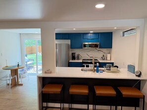 A modern kitchen with blue cabinets, a stainless steel refrigerator, and a marble backsplash. - Modern Austin Retreat with Hot Tub & Outdoor Shower (Austin)