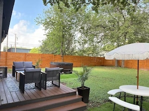 A wooden deck with outdoor furniture, a hot tub, and a covered table with a canopy.