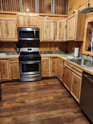 Cocina con armarios de madera, electrodomésticos de acero inoxidable y piso de madera.