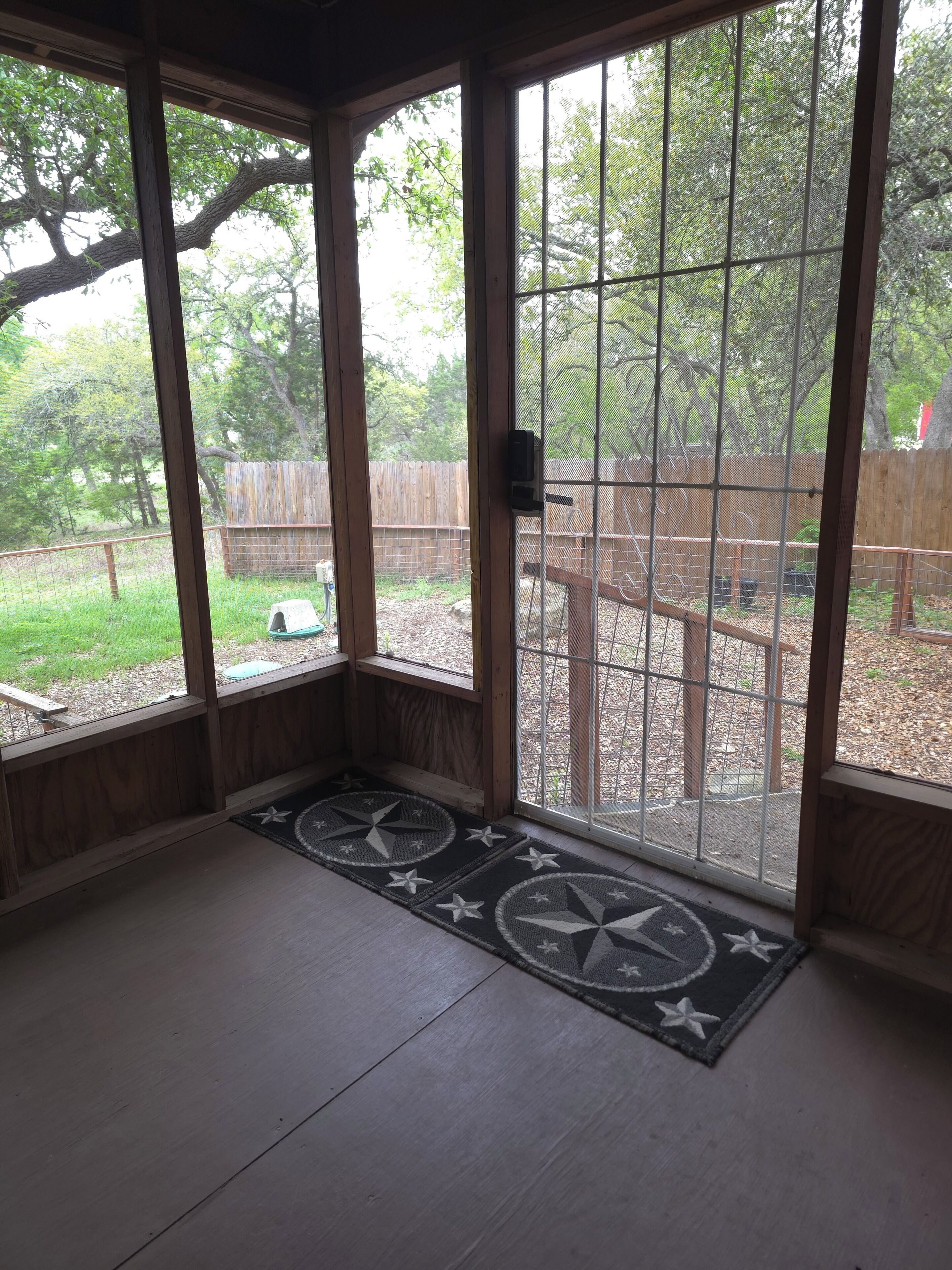 A room with a large window, a wooden door, and a star-patterned doormat.