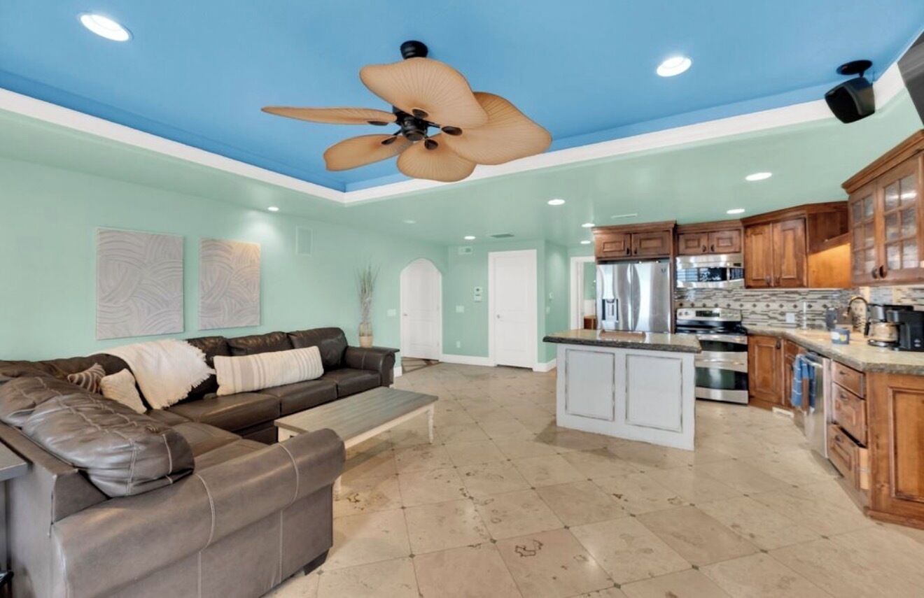A spacious living room with a large sofa, a coffee table, and a ceiling fan.