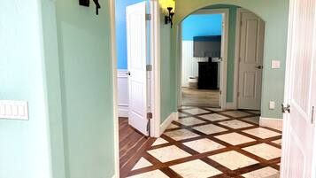 A hallway with a checkered floor pattern, light green walls, and a white door at the end.