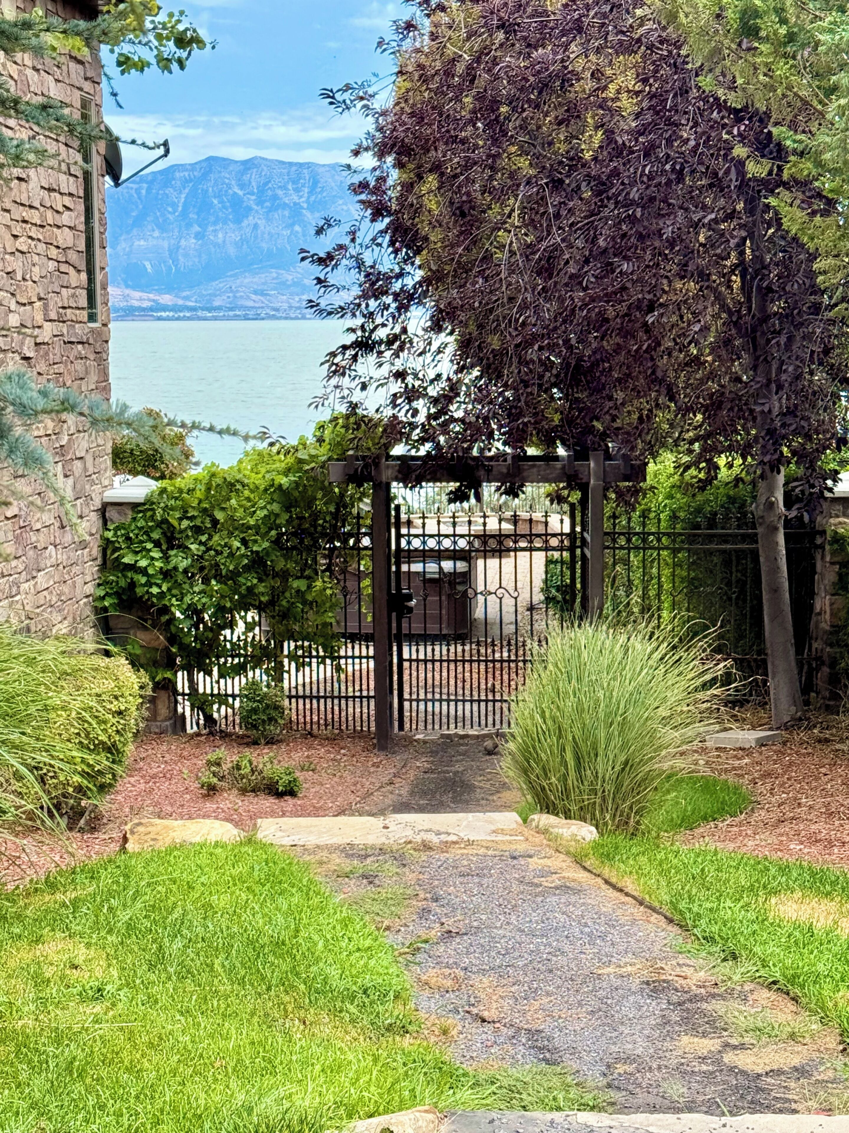 A pathway leading to a gated area with a view of a lake and mountains in the background.