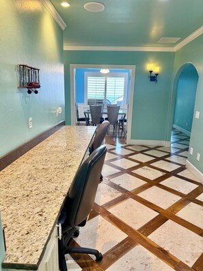 A kitchen with a granite countertop, a dining area with chairs, and a patterned floor.