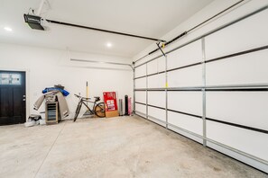 A garage with a white door, a bicycle, a fan, and a box. - New Riverfront Retreat Near Bigfork (Bigfork)