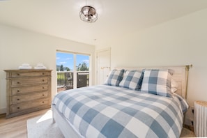 Un dormitorio con cama, cómoda, ventana y lámpara en el techo.