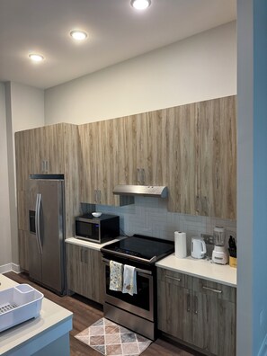 A modern kitchen with wood paneling, stainless steel appliances, and a herringbone tile backsplash. - His Grace Contemporary Living in Truist Park (Atlanta)