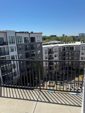 A modern apartment building with multiple balconies and a rooftop pool area. - His Grace Contemporary Living in Truist Park (Atlanta)
