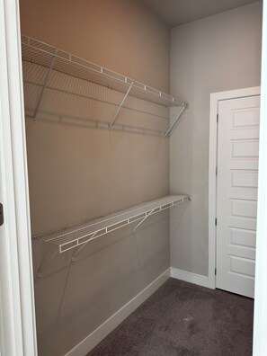 A closet with two metal shelves and a white door. - His Grace Contemporary Living in Truist Park (Atlanta)