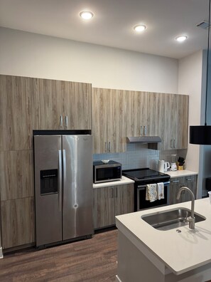 A modern kitchen with a stainless steel refrigerator, a microwave, and an oven. - His Grace Contemporary Living in Truist Park (Atlanta)
