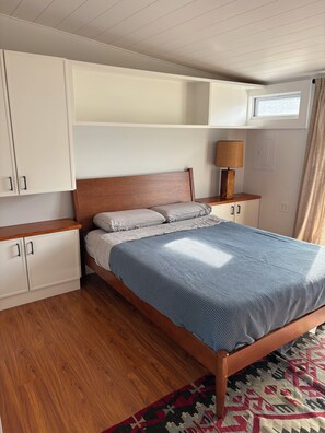 A bedroom with a wooden bed, a nightstand with a lamp, and built-in storage cabinets.
