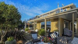 A covered outdoor patio with a dining table, chairs, and potted plants. - Estuary Edge in Mapua a luxurious getaway (Māpua)