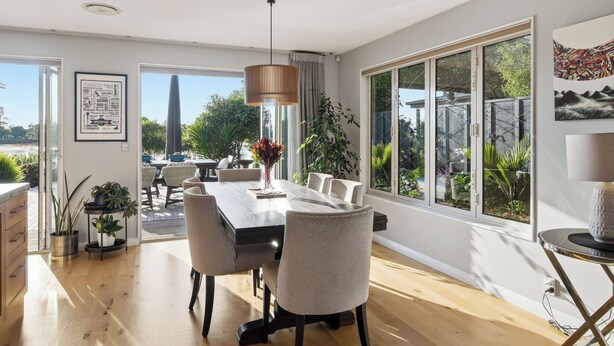 A spacious dining area with a long table, chairs, and a hanging light fixture. - Estuary Edge in Mapua a luxurious getaway (Māpua)