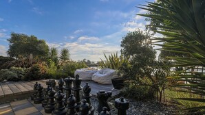 A chessboard set outdoors with a garden and a body of water in the background. - Estuary Edge in Mapua a luxurious getaway (Māpua)