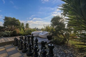 A chessboard set outdoors with a garden and a body of water in the background. - Estuary Edge in Mapua a luxurious getaway (Māpua)