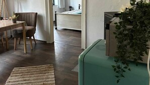 A room with a dining table, chairs, a small rug, a television, and a plant.