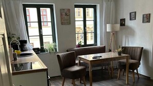 A compact living space with a kitchenette, dining area, and a large window providing natural light.