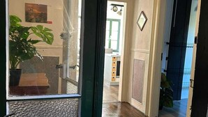 A hallway with wooden flooring, a door with a frosted glass panel, and a fire extinguisher mounted on the door frame.
