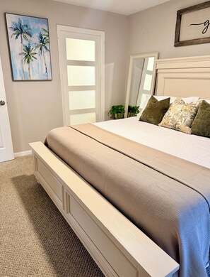 A bedroom with a bed, a door, a mirror, and a painting on the wall. - Family-Friendly Largo Retreat Near Beaches  Sleeps 7 (Largo)