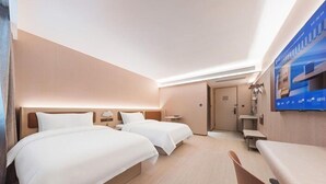 A hotel room with two beds, a desk, and a television. - Hanting Hotel-ShiLaoRen Beach (Qingdao)