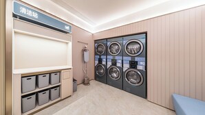 A laundry facility with multiple washing machines, a drying station, and storage bins.