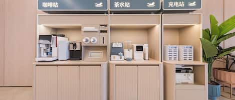 Zona de recepción con quioscos de autoservicio para el registro, una máquina de café e impresora.
