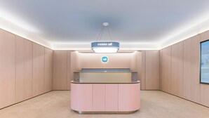 A reception desk with a logo, a hanging light fixture, and a view of the outside through a window.