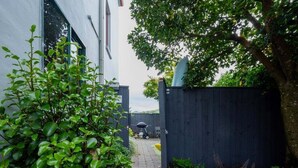A narrow pathway leading to a building with a dark fence and greenery on either side. - Seaview Family Stay Akaroa - Spacious, Sunny & 2 carparks - 2 min walk to waterfront (Akaroa)