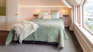 A bedroom with a bed, bedside lamps, a window, and a view of the outside. - Seaview Family Stay Akaroa - Spacious, Sunny & 2 carparks - 2 min walk to waterfront (Akaroa)