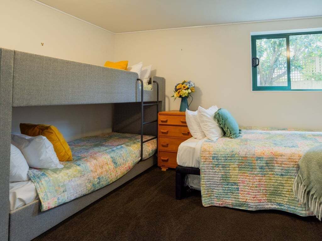 Ein Zimmer mit zwei Etagenbetten, einem Schminktisch und einem Fenster.