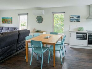A modern living space with a dining area, kitchen, and a large window providing natural light. - Seaview Family Stay Akaroa - Spacious, Sunny & 2 carparks - 2 min walk to waterfront (Akaroa)