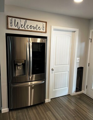 A stainless steel refrigerator with a water dispenser and a 'Welcome' sign above it. - Cozy Country Oasis (Guyton)