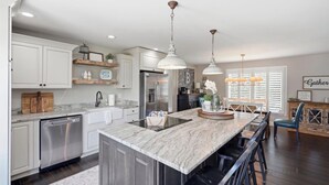 Una cucina moderna con isola centrale, elettrodomestici in acciaio inossidabile e illuminazione a sospensione.