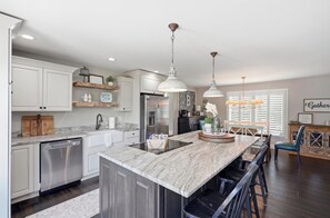 A modern kitchen with a central island, stainless steel appliances, and pendant lighting. - Lazy Dayz - on Lake Keowee with dock, pool, and hot tub (Seneca)