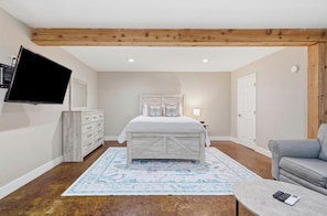 A bedroom with a bed, a dresser, a television, a gray sofa, and a patterned rug. - Lazy Dayz - on Lake Keowee with dock, pool, and hot tub (Seneca)