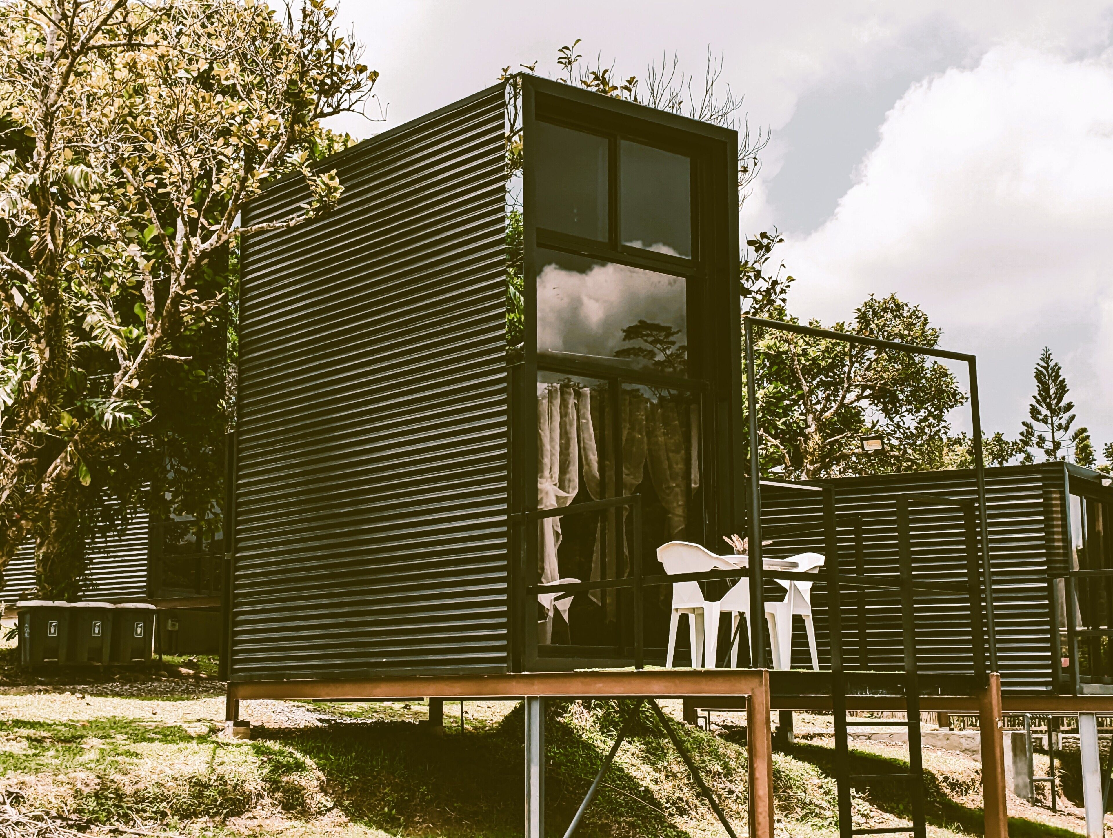 Une petite cabane moderne dotée d’une grande fenêtre, d’une porte et d’un petit espace porche.