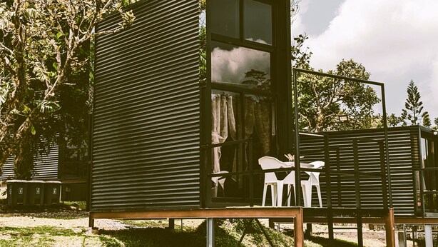 A small, modern cabin with a large window, a door, and a small porch area.