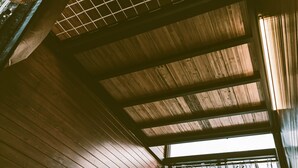 A room with wooden slats on the ceiling and a window with curtains.